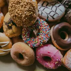 Kolorowe pączki, każdy z nich to mała bomba kaloryczna. Cukier, lukier, posypki – ile kalorii kryje się w tej słodkiej przyjemności?