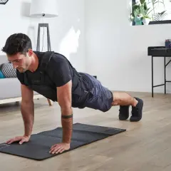 Mężczyzna w kamizelce obciążeniowej wykonuje pompki, wzmacniając biceps i klatkę piersiową.