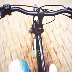 Widok z perspektywy rowerzysty. Ręka na kierownicy, dżinsy i droga w tle. Jak ustawić kierownicę w rowerze?