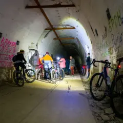 Grupa rowerzystów eksploruje mroczną, graffiti-pokrytą podziemną trasę rowerową.