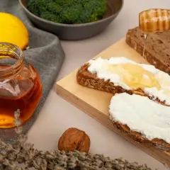 Słoik miodu, cytryna, brokuły i chleb z serkiem i miodem. Czy miód jest zdrowy? Tak, zwłaszcza gdy jest naturalny i spożywany z umiarem.