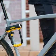 Solidne, żółto-czarne zapięcie rowerowe OnGuard zabezpiecza ramę szarego roweru. Idealne pytanie: jakie zapięcie do roweru wybrać?