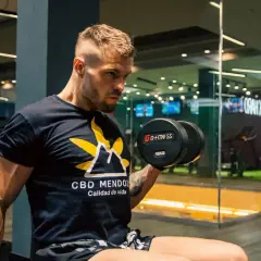 Mężczyzna ćwiczy z hantlem 15kg. Zastanawiasz się, ile trwa trening na siłowni? Kluczowe jest efektywne wykorzystanie czasu.