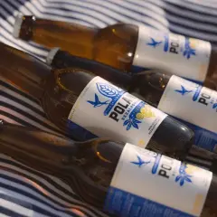 Butelki piwa bezalkoholowego na kocu w paski. Czy piwo bezalkoholowe nawadnia? Idealne na upalny dzień.