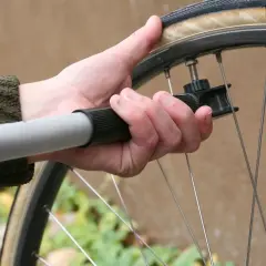 Dłoń trzyma pompkę rowerową, by zapewnić prawidłowe ciśnienie w oponach.