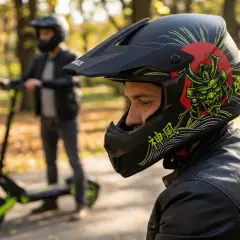 Mężczyzna w kasku z motywem samuraja na hulajnodze elektrycznej. Czy na hulajnodze elektrycznej trzeba mieć kask? Tak, dla bezpieczeństwa!