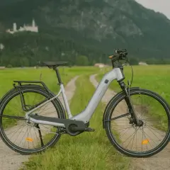 Szary rower elektryczny na drodze polnej z zamkiem w tle.