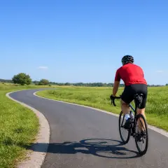 Kolarz w czerwonej koszulce przemierza malowniczą trasę, ciesząc się słońcem i zielenią. To idealne miejsce, by poczuć się jak w rowerowej stolicy Polski.