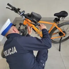 Policjant sprawdza, czy na rower elektryczny trzeba mieć prawo jazdy. Pomarańczowy rower górski z bagażnikiem.