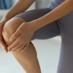 Dłoń obejmująca kolano w legginsach.
