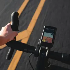 Dłoń na kierownicy roweru, nawigacja pokazuje mapę tras rowerowych w Krakowie.