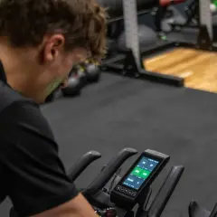 Mężczyzna na rowerze stacjonarnym sprawdza dane treningowe. Czy to już czas na test FTP?