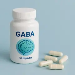 Biała butelka z napisem GABA i grafiką mózgu, obok kilka kapsułek. Suplement diety GABA.
