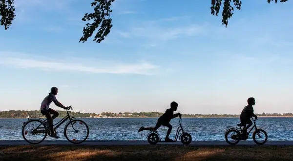 Dzieci na rowerach i hulajnogach nad jeziorem. Idealny rower dla 13 latka to taki, który zapewni mu radość z jazdy.