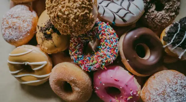 Kolorowe pączki, każdy z nich to mała bomba kaloryczna. Cukier, lukier, posypki – ile kalorii kryje się w tej słodkiej przyjemności?