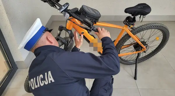 Policjant sprawdza, czy na rower elektryczny trzeba mieć prawo jazdy. Pomarańczowy rower górski z bagażnikiem.