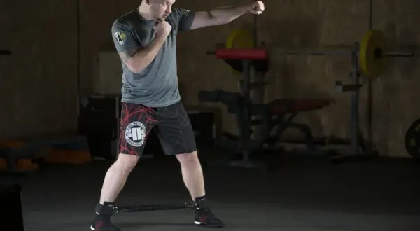 Mężczyzna ćwiczy w siłowni, wykonując ciosy. To świetny przykład, jak trening HIIT co to jest, może być efektywny.