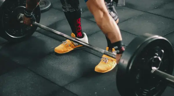 Siłacz przygotowuje się do podniesienia sztangi. Czy crossfit jest tego wart? Intensywny trening, który buduje siłę i wytrzymałość.