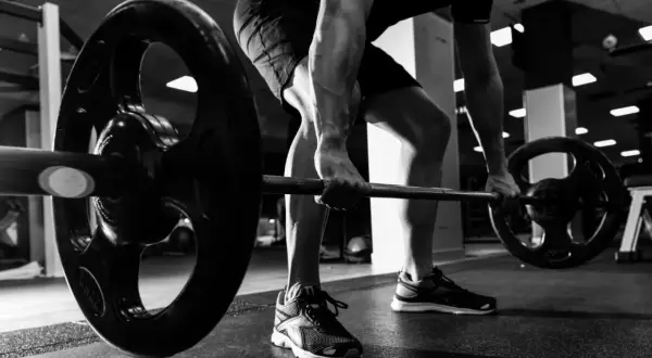 Mężczyzna wykonuje ćwiczenie rack pull, podnosząc ciężar z podłogi.