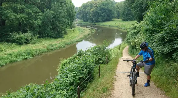 Rowerzysta na ścieżce w Parku Mużakowskim. Malownicze trasy rowerowe wzdłuż rzeki zachęcają do aktywnego wypoczynku.