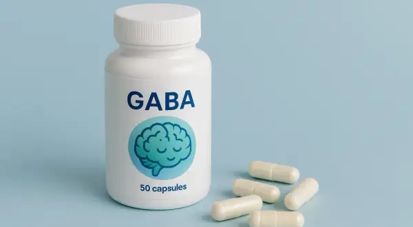 Biała butelka z napisem GABA i grafiką mózgu, obok kilka kapsułek. Suplement diety GABA.