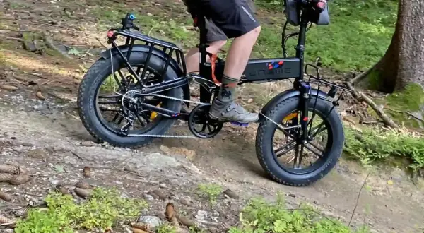 Rowerzysta na rowerze elektrycznym z grubymi oponami pokonuje leśną trasę rowerową.
