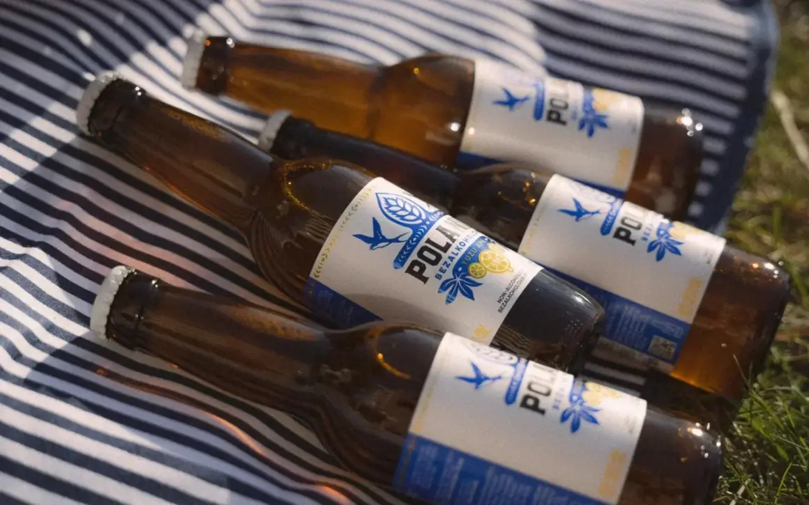 Butelki piwa bezalkoholowego na kocu w paski. Czy piwo bezalkoholowe nawadnia? Idealne na upalny dzień.