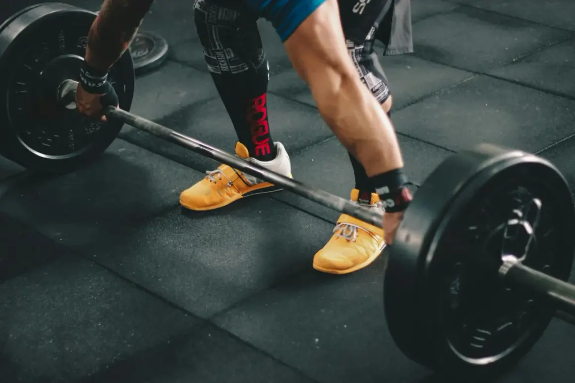 Siłacz przygotowuje się do podniesienia sztangi. Czy crossfit jest tego wart? Intensywny trening, który buduje siłę i wytrzymałość.