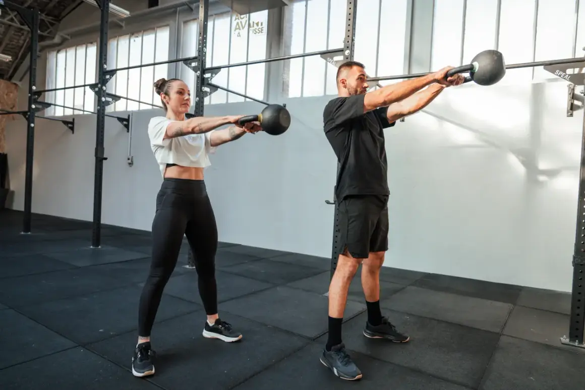 Kobieta i mężczyzna ćwiczą z kettlebellami w siłowni.