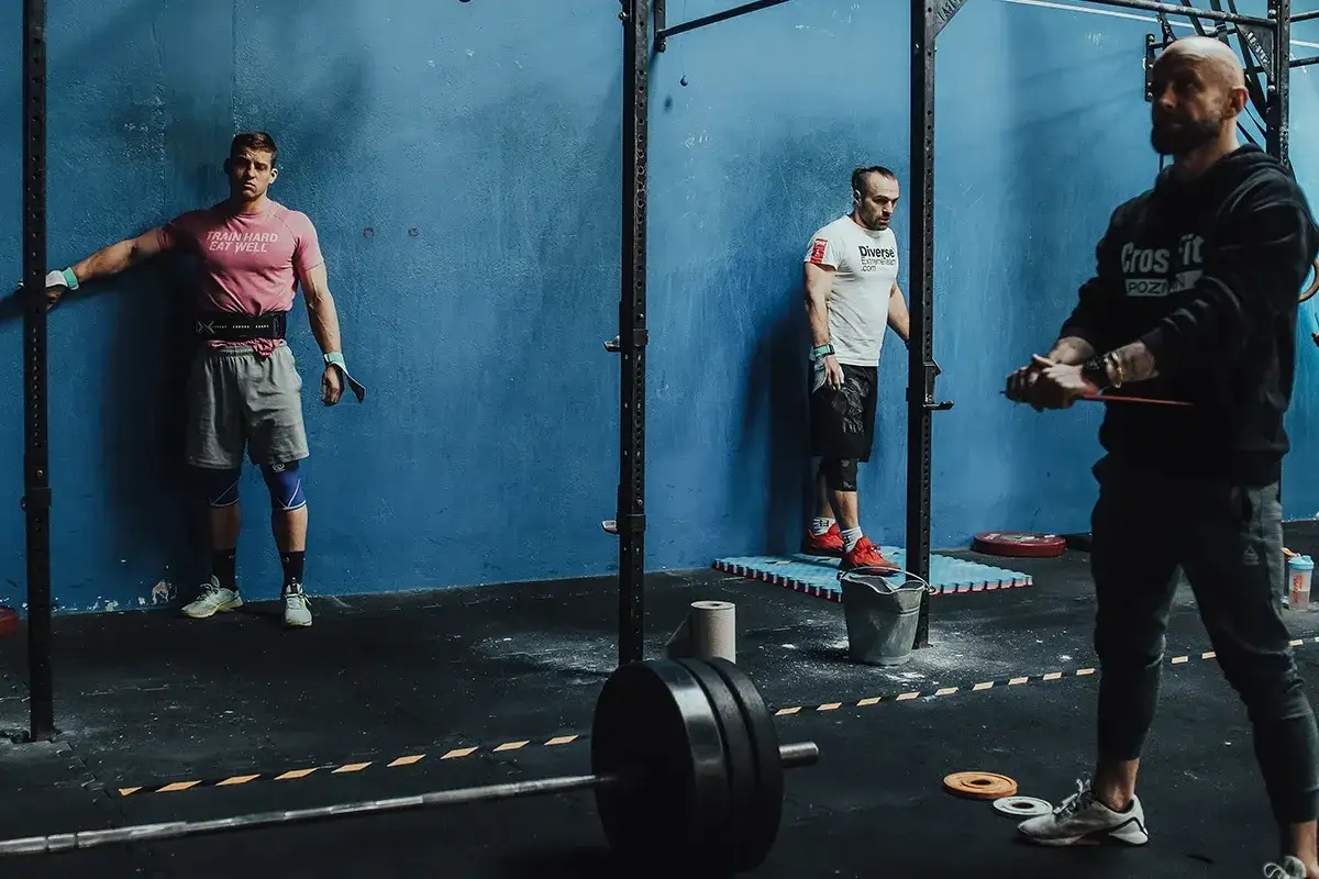 Trzech mężczyzn w różnym wieku trenuje crossfit. Każdy z nich jest w innej fazie ćwiczeń, co pokazuje, że crossfit dla kogoś jest dostępny.