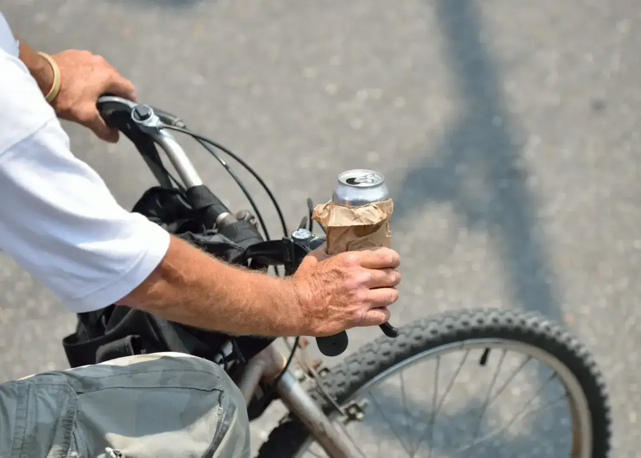 Rowerzysta trzyma puszkę owiniętą w papier. Czy można jechać rowerem po alkoholu? To pytanie, na które odpowiedź jest jednoznaczna: nie.