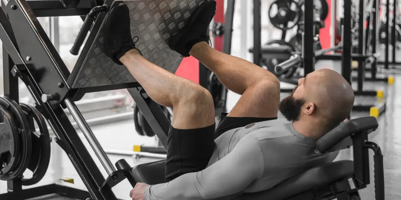 Mężczyzna ćwiczy nogi na maszynie typu leg press. To część treningu push pull legs, skupiająca się na sile i budowaniu mięśni nóg.