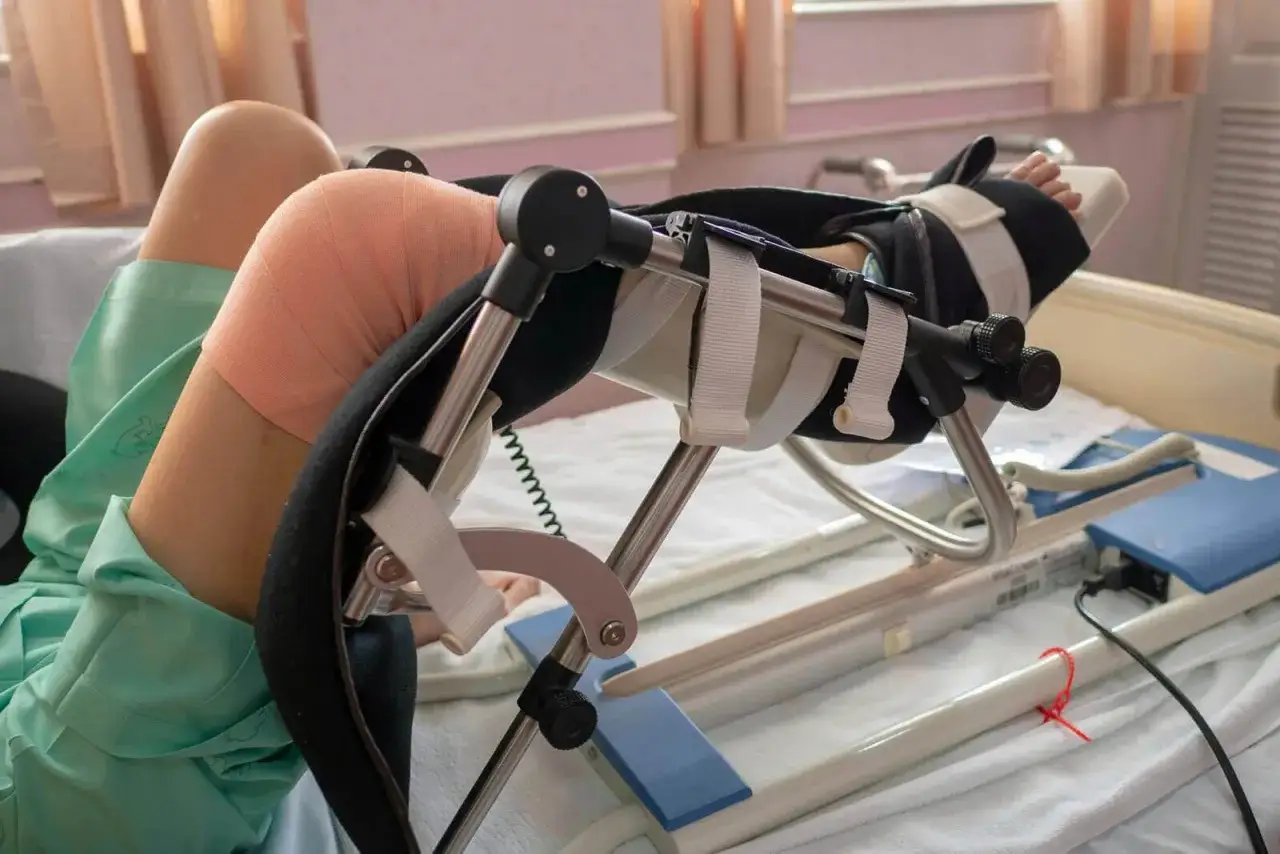 Pacjent po endoprotezie kolana wykonuje ćwiczenia na specjalistycznym urządzeniu. Rehabilitacja jest kluczowa.