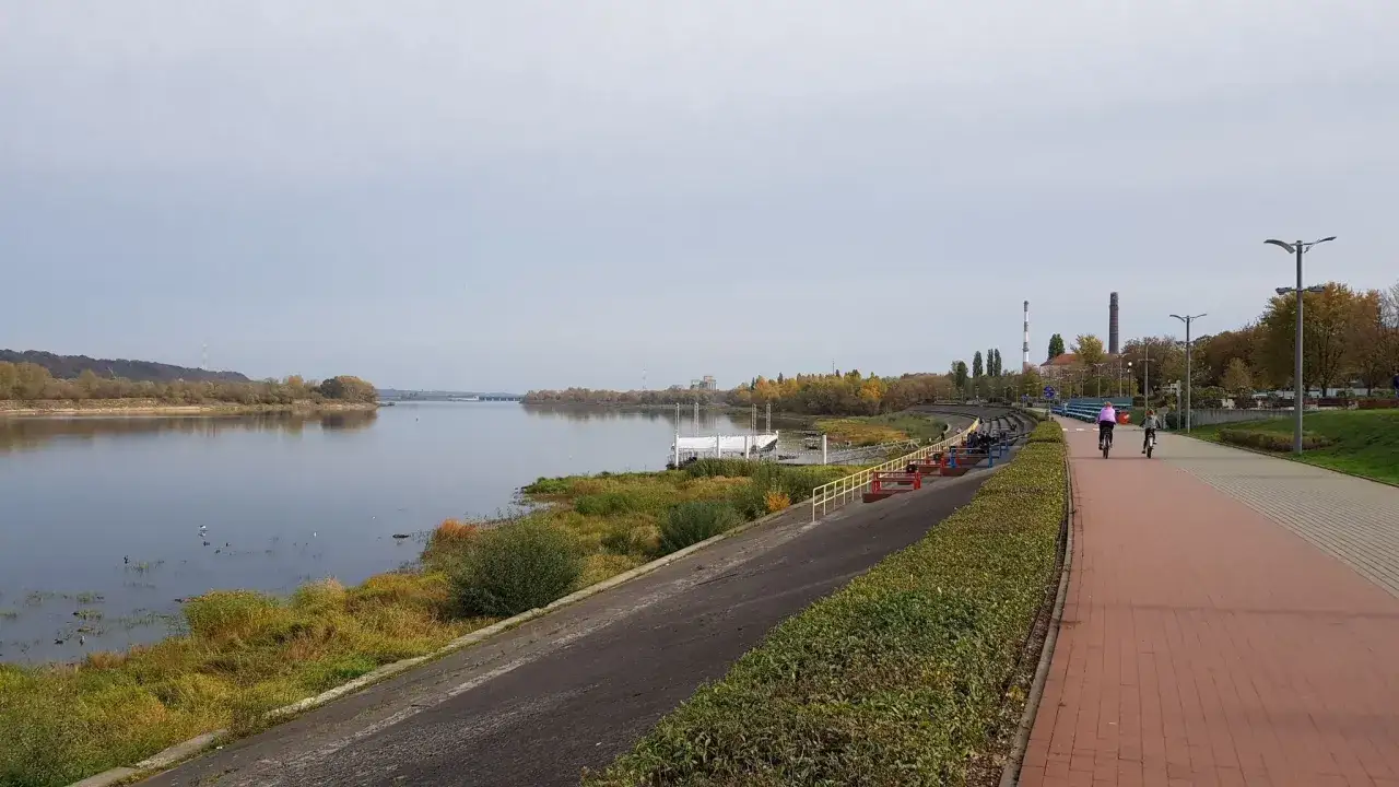 Dwie osoby na rowerach przemierzają malownicze trasy rowerowe Toruń wzdłuż Wisły.