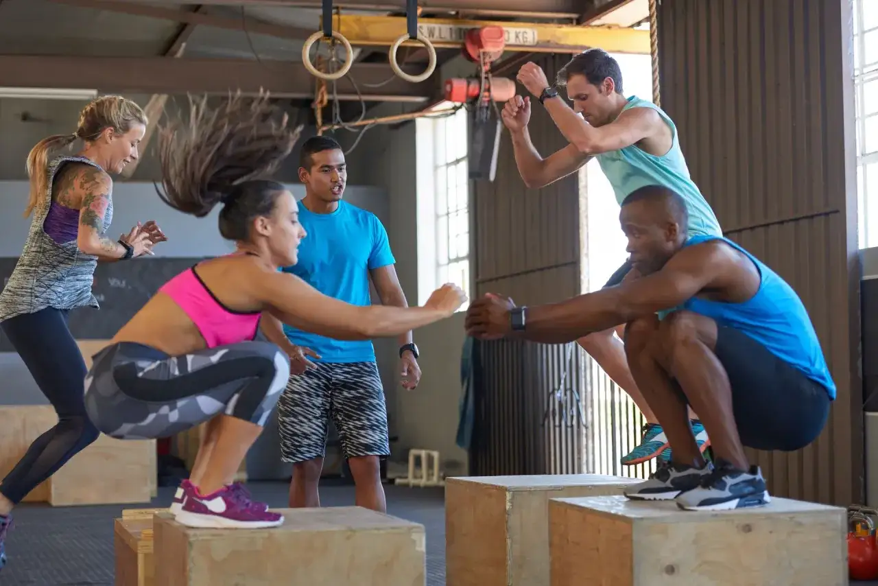Grupa ludzi ćwiczy skoki na skrzynie. Czy crossfit jest zdrowy? Intensywny trening pokazuje, że tak, jeśli jest wykonywany prawidłowo.