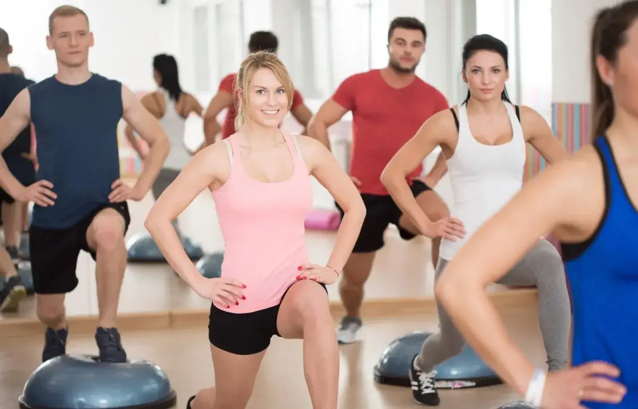 Grupa osób ćwiczy na poduszkach BOSU. To właśnie fitness co to – aktywność fizyczna dla zdrowia i dobrego samopoczucia.