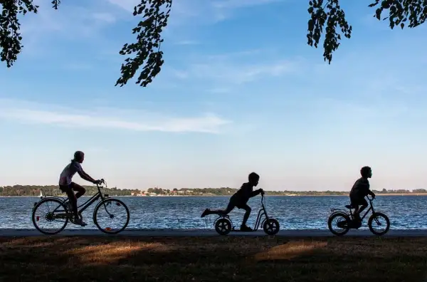 Dzieci na rowerach i hulajnogach nad jeziorem. Idealny rower dla 13 latka to taki, który zapewni mu radość z jazdy.
