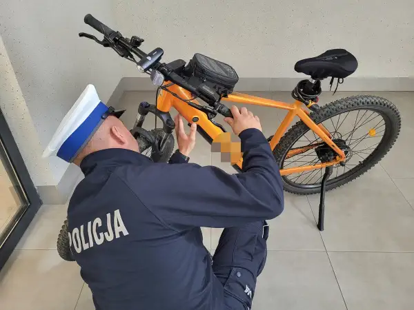 Policjant sprawdza, czy na rower elektryczny trzeba mieć prawo jazdy. Pomarańczowy rower górski z bagażnikiem.
